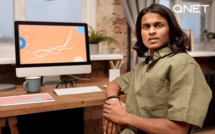 A-man-sitting-in-front-of-his-computer-with-a-sales-graph-going-upwards-on-the-screen