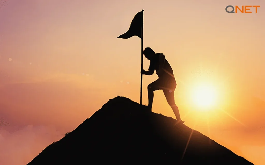 A silhouette of a young businessman overcoming challenges and reaching the summit