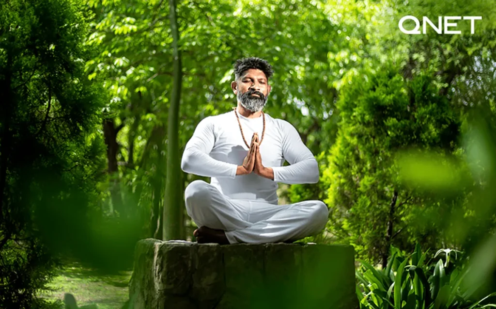 An ancient man doing yoga on a stone in a jungle