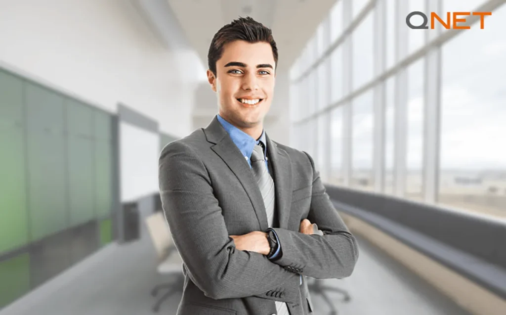 A young man in a suit folding his hands looking at the camera