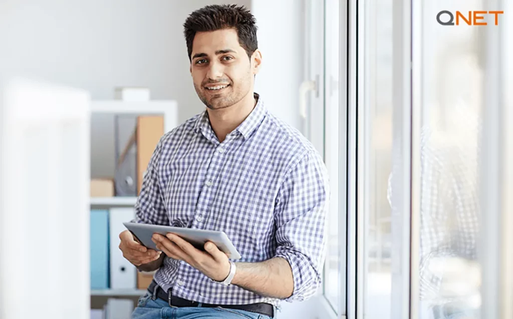 A young QNET direct seller with a tablet in his hand in an office